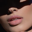 Błyszczyk do ust Hedonista Diamonds For Breakfast Lipgloss – jasny, transparentny różowy połysk na ustach modelki