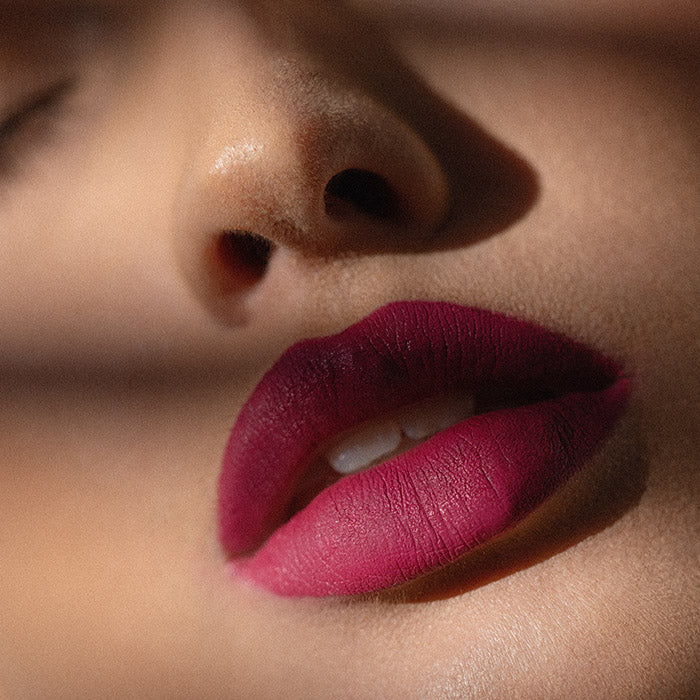 Matowa pomadka Hedonista About Her Lipstick – głęboki malinowo-śliwkowy odcień na ustach modelki