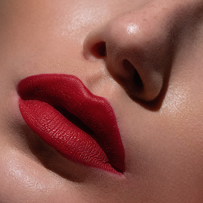 Matowa pomadka Hedonista Crazy In Love Lipstick – głęboki, intensywny czerwony odcień na ustach modelki